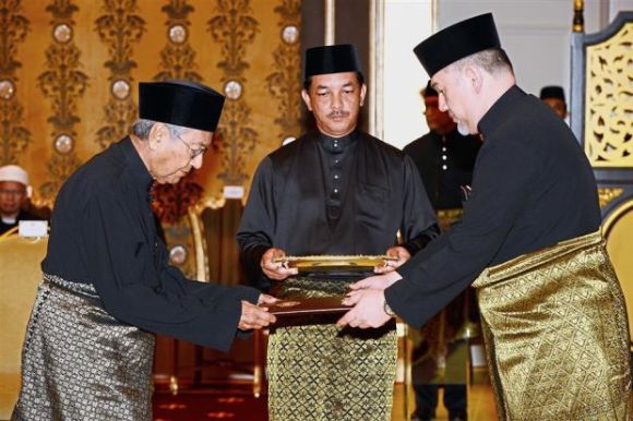 Dr Mahathir Mohamad receives the instrument of appointment from the Yang di-Pertuan Agong, Sultan Muhammad V